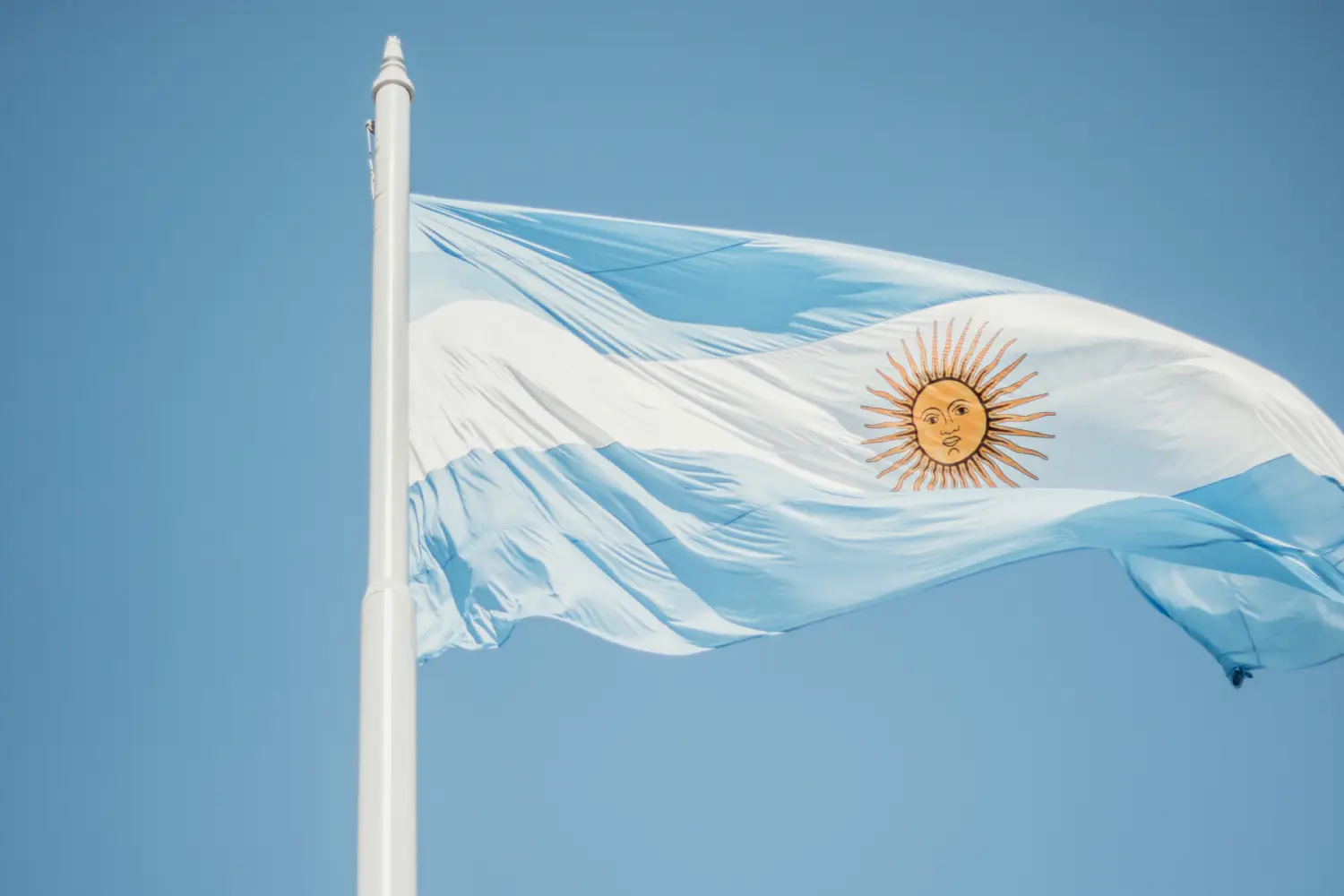 the flag of argentina is flying high in the sky