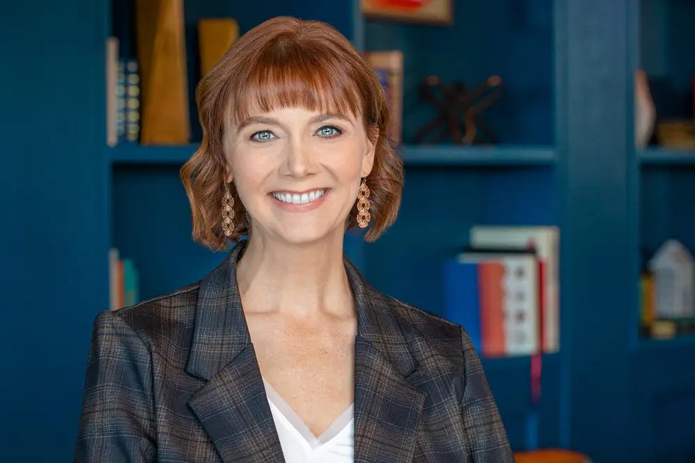 a woman with red hair wearing a suit and earrings