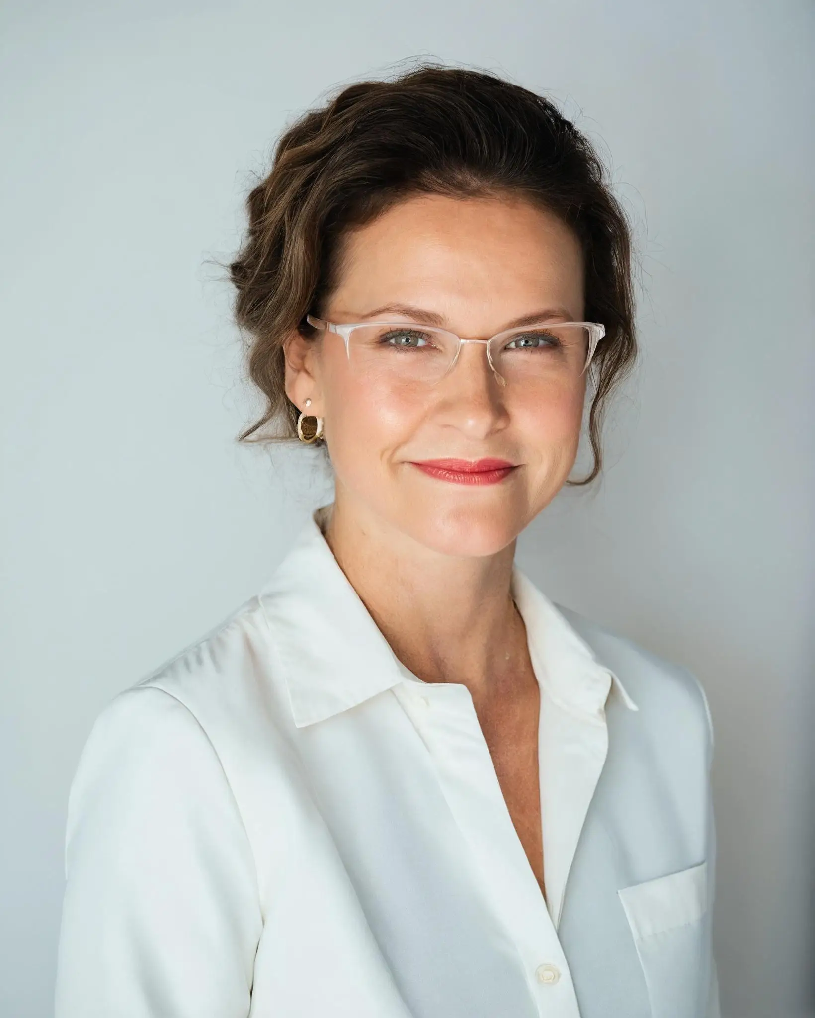 a woman wearing glasses and a white shirt